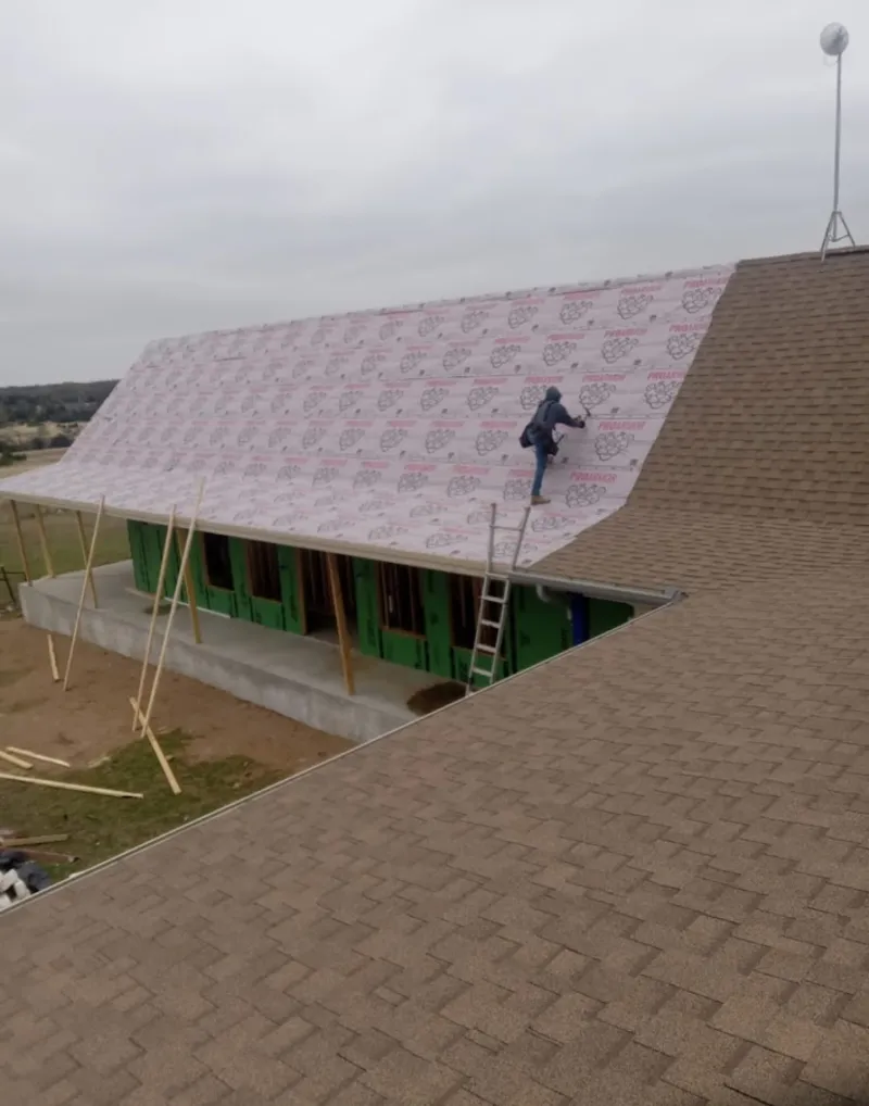 Worker preparing underlayment for a metal roof installation in Saratoga